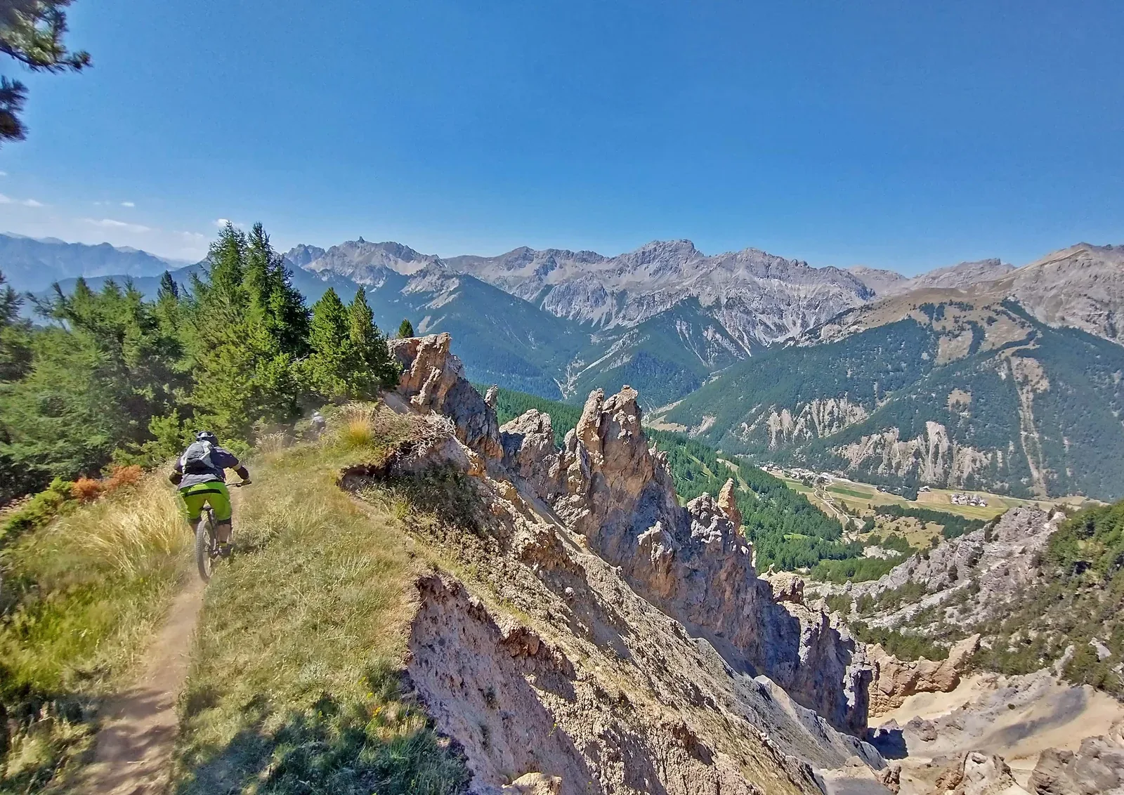 Mountain biker descending a rocky ridge trail above the valley