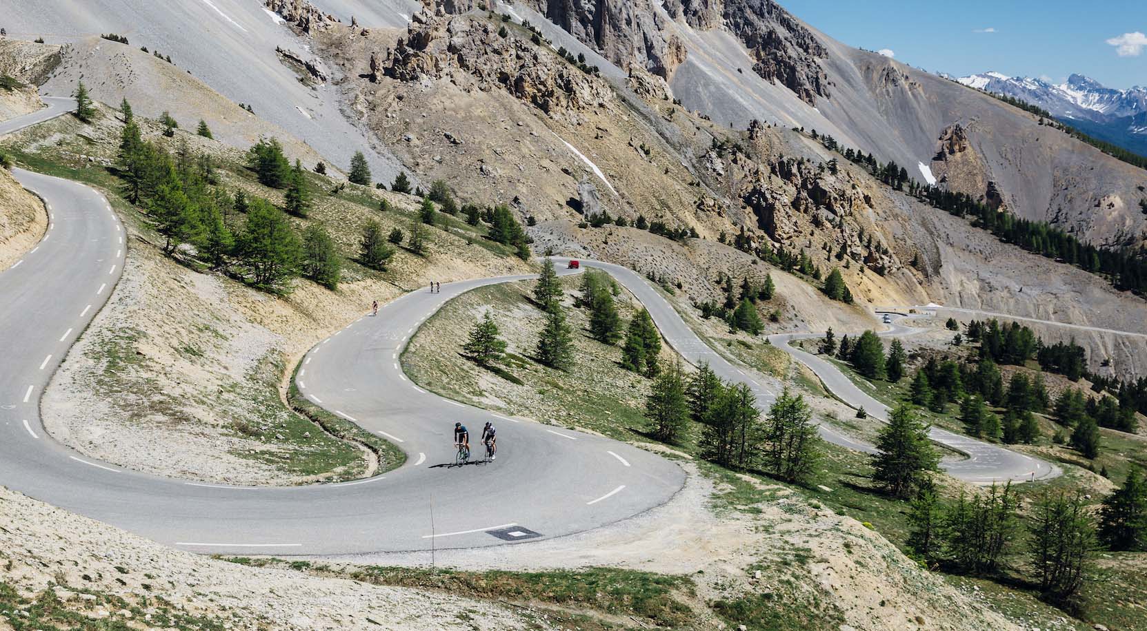 Two road cyclists riding a switchback at the Col d'Izoard